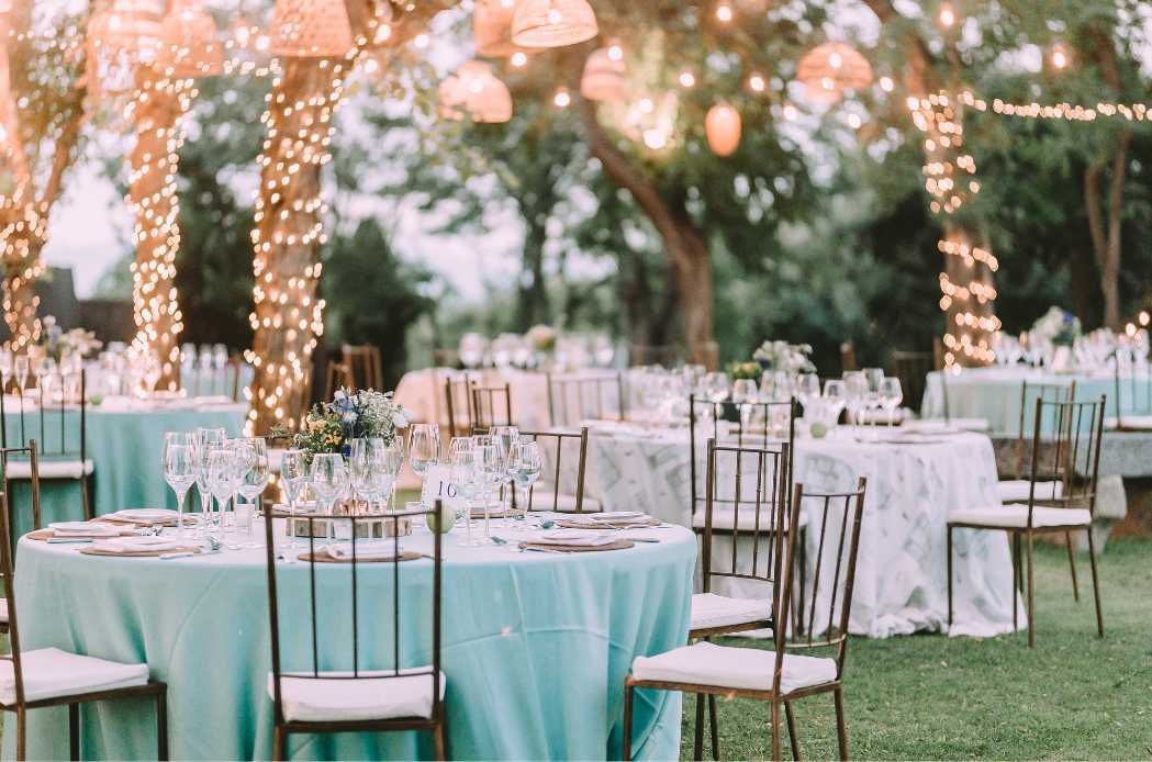 Wedding dining tables decorated with lights in a château courtyard